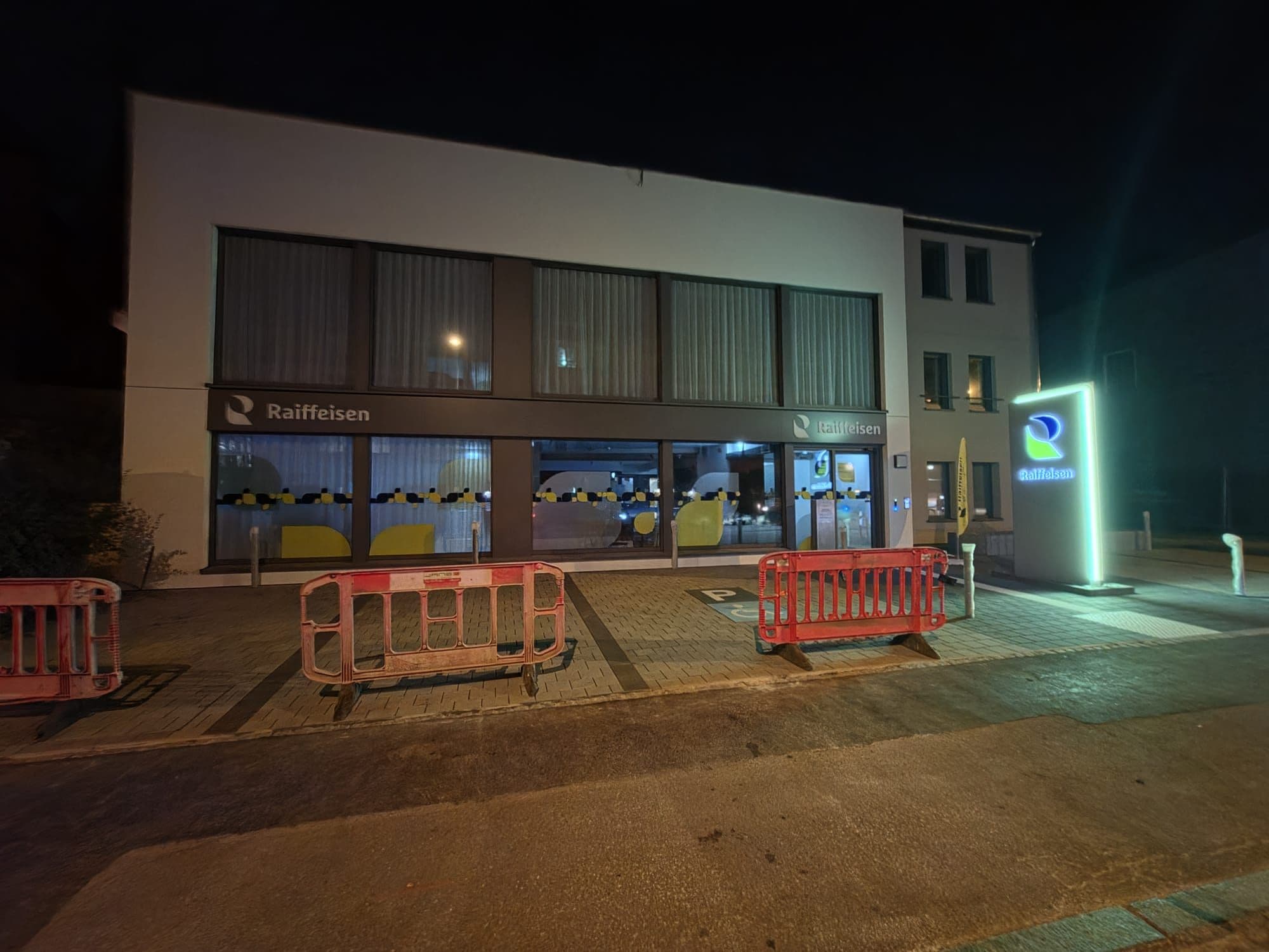 Agence Raiffeisen de Wiltz de nuit, vitrines et totem éclairés