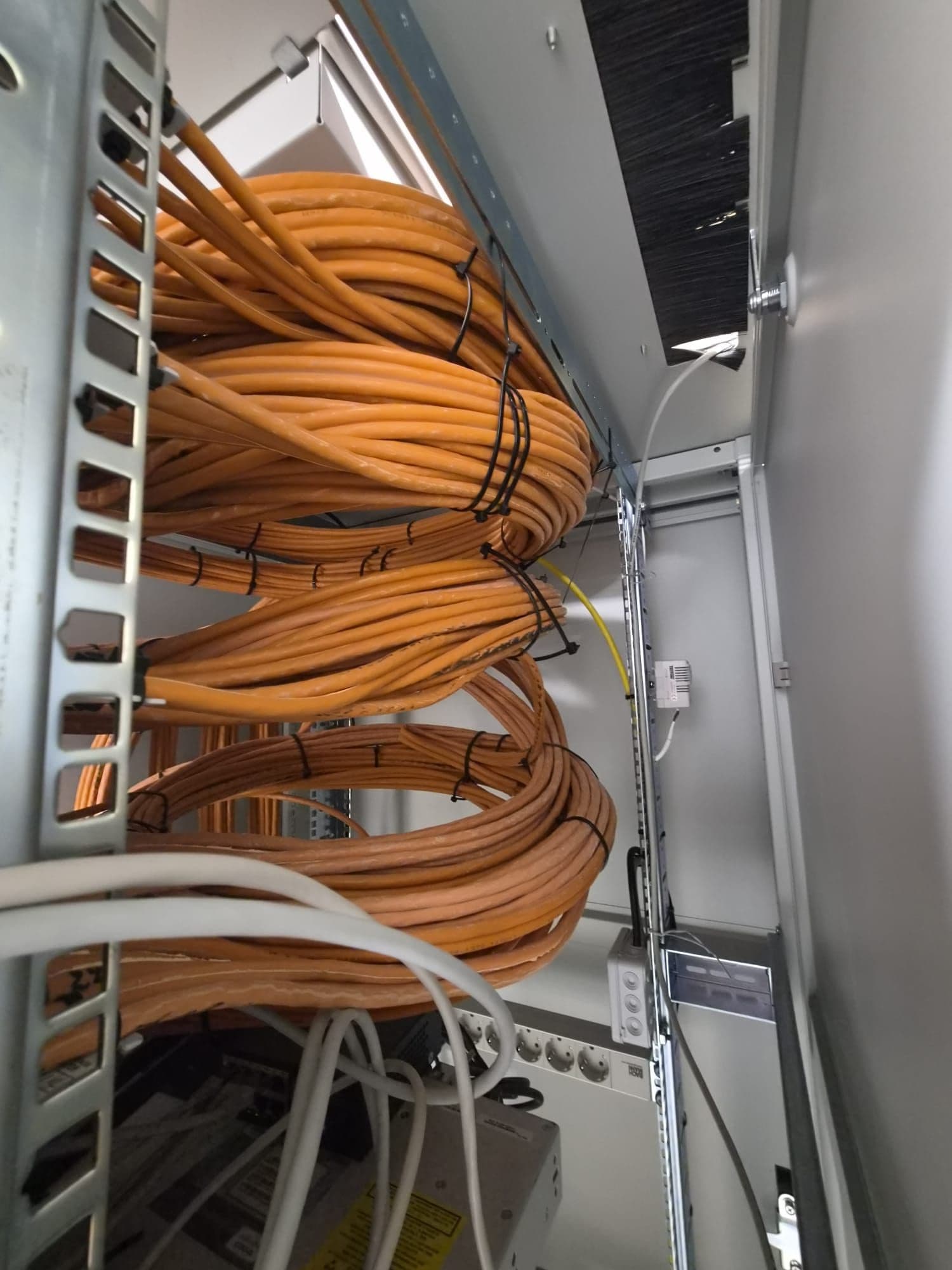 Orange network cables neatly routed in a technical rack